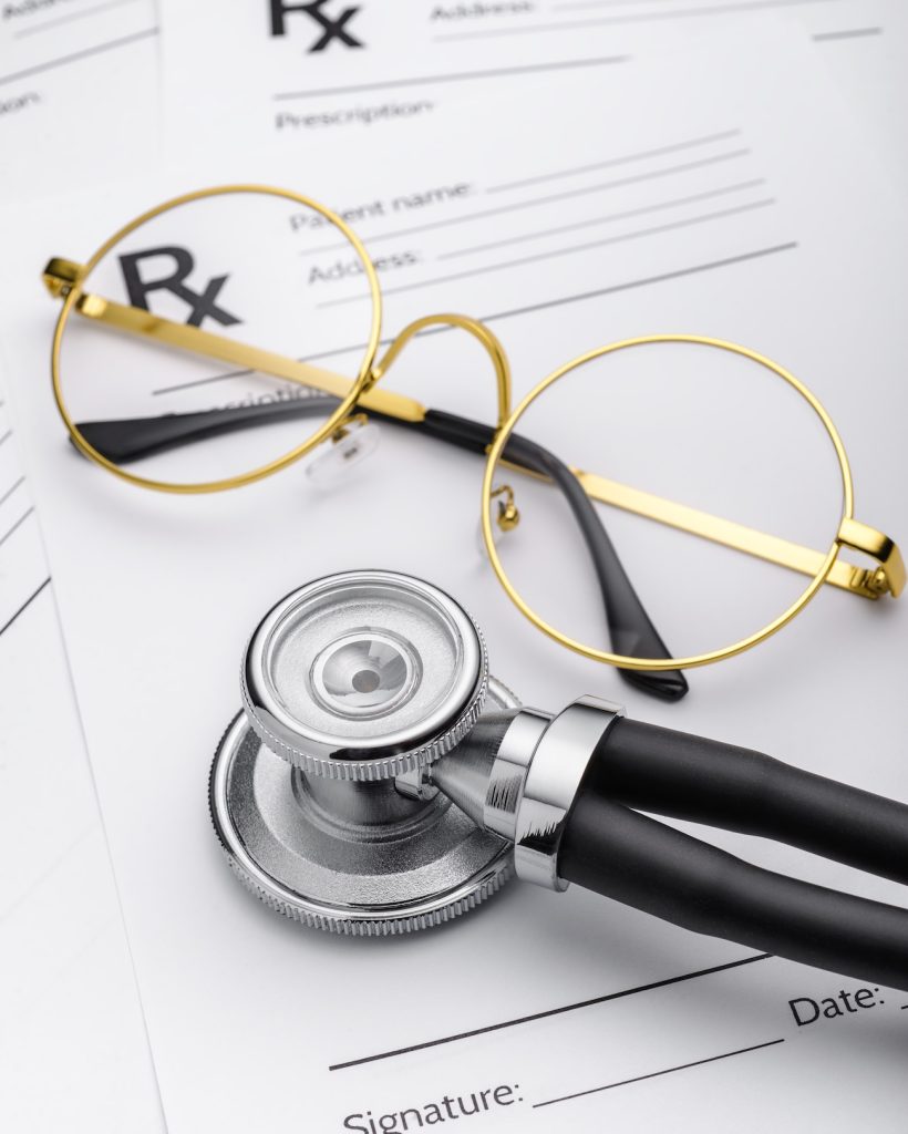 Medical stethoscope and prescription form with glasses.